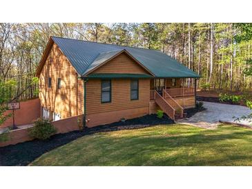 Charming house featuring wood siding, a green metal roof, front porch, and a well-manicured lawn at 5070 Smithfield Rd, Bowdon, GA 30108