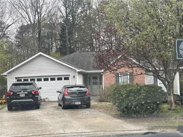 Charming single-story home with vinyl siding, brick accents, a two-car garage, and mature trees at 1116 Venice Cir, Lawrenceville, GA 30043