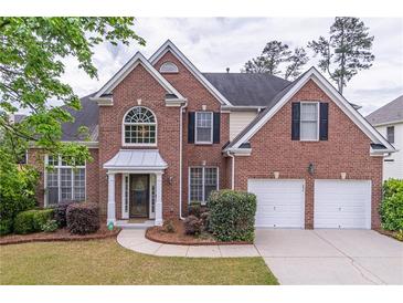 Charming two-story brick home boasts a well-manicured lawn and two-car garage at 115 Westbury Ln, Johns Creek, GA 30005