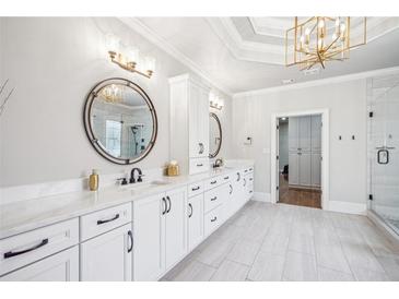 Bright bathroom with double vanity, white cabinets, marble countertops, and a modern, gold light fixture at 5945 Boulder Bluff Dr, Cumming, GA 30040