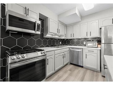 Modern kitchen features stainless steel appliances, light gray cabinets and a black hexagon tile backsplash at 2965 Pharr Court South Nw # 304, Atlanta, GA 30305