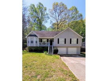 Charming split-level home with grey siding, well-maintained lawn and two-car garage at 1084 Whistle Dr, Austell, GA 30106