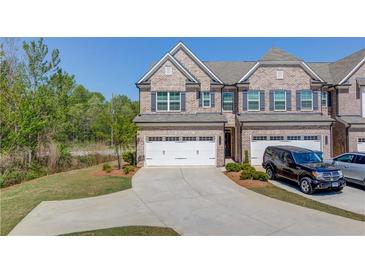 Two story brick townhome with a large driveway, two car garage, and well-manicured landscaping at 2378 Morgan Creek Rd, Buford, GA 30519
