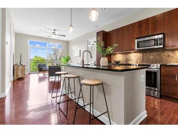 Modern kitchen with dark cabinets, stainless appliances, and an island with barstool seating that opens to living area at 711 Cosmopolitan Ne Dr # 347, Atlanta, GA 30324