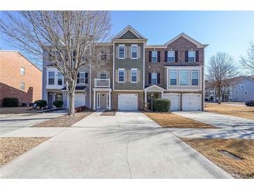 View of the townhome exteriors featuring attached garages and well-maintained lawns on a sunny day at 1294 Park Pass Way, Suwanee, GA 30024