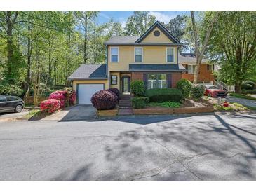 Charming yellow two-story home with well-maintained landscaping, mature trees, and an attached garage at 2008 Falcon Glen Ct, Alpharetta, GA 30022