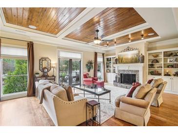 Spacious living room with a fireplace, wood floors, and custom wood tray ceilings at 320 Town Center Ave # U206B, Suwanee, GA 30024