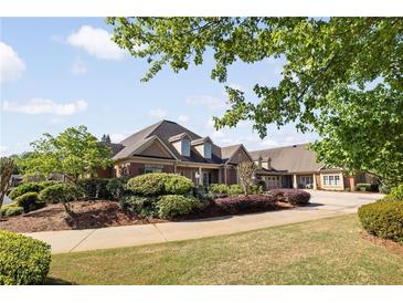 Charming brick home with lush landscaping and a well-manicured lawn, nestled under a bright, partly cloudy sky at 2550 Ballantrae Cir, Cumming, GA 30041