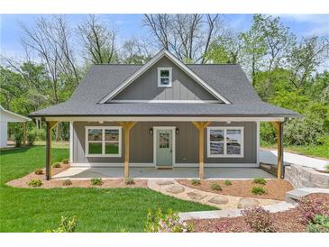 Charming home featuring a covered porch with wooden support beams, complemented by a landscaped front yard at 5224 W Mountain St, Stone Mountain, GA 30083