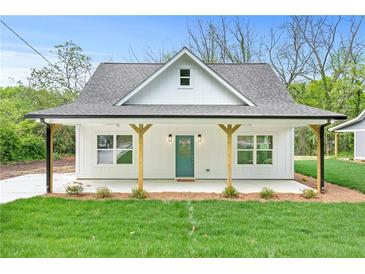 Charming single-story home featuring a covered front porch, green lawn, and a teal front door at 5232 W Mountain St, Stone Mountain, GA 30083