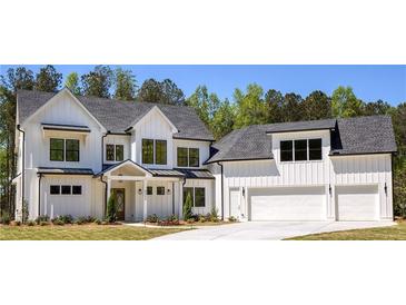 Stunning two-story modern farmhouse featuring a three car garage, manicured lawn and bright white siding at 4059 Yellow Creek Trl, Cumming, GA 30028