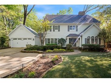 Charming two-story home featuring a lush landscaped yard, attached garage and inviting front porch at 4477 Jett Nw Rd, Atlanta, GA 30327