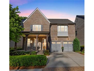 Charming two-story brick home featuring a covered front porch and a two-car garage with updated doors at 6454 Meridian Way, Atlanta, GA 30328