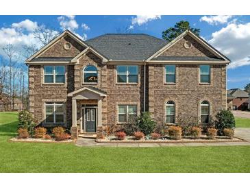 Beautiful brick home with a manicured lawn, mature trees and blue sky at 4580 Cloister Cir, Hampton, GA 30228