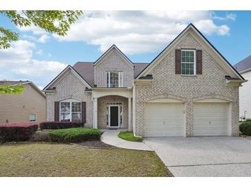 Charming two-story brick home featuring a two-car garage, landscaped yard and inviting front entrance at 5450 Fieldfreen Dr, Cumming, GA 30028