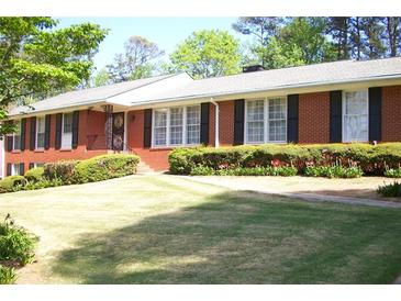 Charming brick home features a well-manicured lawn, lush shrubs, and black window shutters at 1568 Rainier Falls Ne Dr, Atlanta, GA 30329