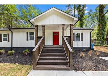 Inviting front entrance features a red door and wooden steps, complemented by the home's charming exterior and well-maintained landscaping at 2798 Hutchins Rd, Lawrenceville, GA 30044