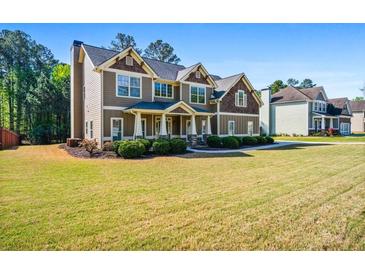 Beautiful two-story home featuring manicured lawn, lush landscaping, and inviting front porch at 1041 Sweetwater Bridge Cir, Douglasville, GA 30134