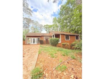 Charming one-story home with wood siding and a well-landscaped front yard surrounded by trees at 1445 Diplomat Dr, Riverdale, GA 30296