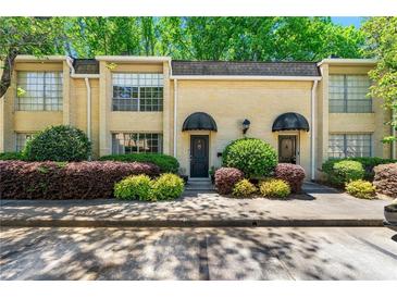 Charming townhome featuring a manicured front yard and a classic brick facade with black awnings above the entries at 5400 Roswell Rd # J2, Atlanta, GA 30342