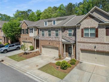 A street view of charming brick townhomes with attached garages and manicured landscaping in a well maintained community at 1983 Silver Birch Se Dr, Smyrna, GA 30080