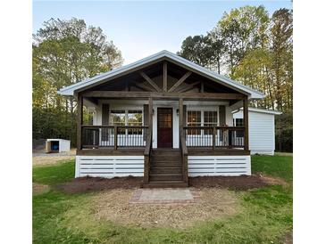 Charming cottage-style home with a covered porch, exposed beams, and manicured lawn at 505 Cedar Creek Nw Rd, Cartersville, GA 30121