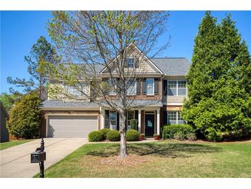 Inviting two-story home with a well-manicured lawn and a charming brick facade, complemented by mature trees and landscaping at 5075 Chase Ln, Cumming, GA 30040