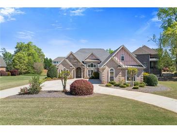 Charming brick home with lush landscaping, a circular driveway, and a well-manicured lawn at 755 Peninsula Overlook, Hampton, GA 30228