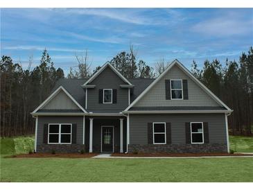 Beautiful two-story home with dark siding, black shutters, covered entry, and a manicured lawn at 80 Hawthorn Ln, Covington, GA 30014
