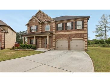 Two-story brick home featuring a two-car garage and well-maintained landscaping in the front yard at 811 Holly Mist Ct, Loganville, GA 30052