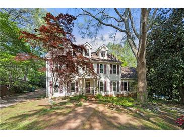 Charming two-story home with white siding, dormer windows, and a lush front yard with mature trees at 6048 Kings Mountain Way, Tucker, GA 30087
