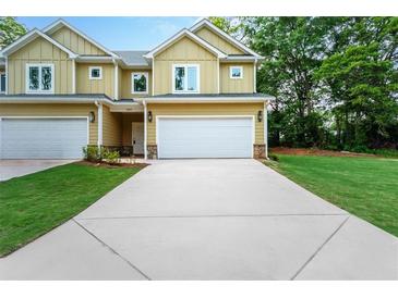 Charming new construction townhouse with a two-car garage, manicured lawn, and inviting curb appeal at 6884 Robinson St, Lithonia, GA 30058