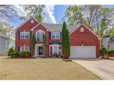 Charming two-story red brick home featuring a well-manicured lawn, shutters, and attached two car garage at 725 Martin Field Dr, Lawrenceville, GA 30045