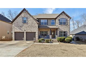 Charming two-story home featuring a brick facade, covered porch, and well-manicured landscaping at 527 Mossycup Dr, Fairburn, GA 30213