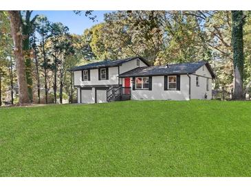 Charming two-story home boasts a white exterior, black trim, inviting red door, and a spacious green lawn at 1971 Westley Dr, Riverdale, GA 30296