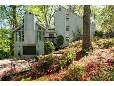 Charming home with a lush, landscaped yard, a private garage, and a wooden stairway to front door at 3727 Cline Se Dr, Smyrna, GA 30082