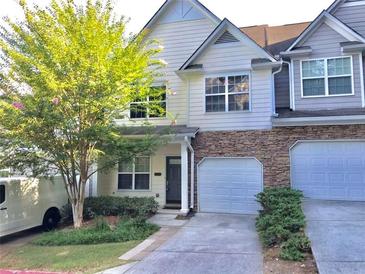 Charming townhome featuring a stone accent, attached garage, and a well-maintained front yard at 1975 Hoods Fort Nw Cir # 24, Kennesaw, GA 30144