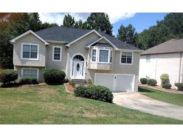 Two-story home featuring an attached garage, a manicured lawn and mature trees at 9399 Whaleys Lake Ln, Jonesboro, GA 30238