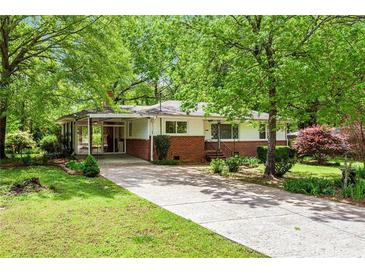 Charming single-story home with a brick facade, covered carport and a long driveway lined with mature trees at 3800 Whitaker Ln, Lithia Springs, GA 30122
