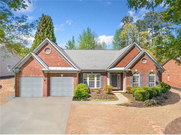 Charming brick home featuring a two-car garage, landscaped yard, and inviting front entrance at 1330 Badingham Dr, Cumming, GA 30041