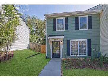 Charming two-story townhouse featuring light-green siding, black shutters, and a well-maintained front lawn at 1021 Windy Oaks Se Ct, Smyrna, GA 30080