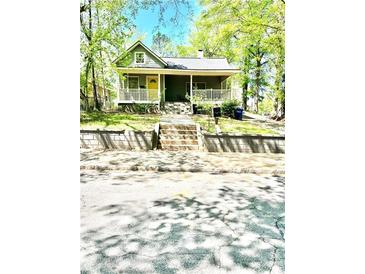 Charming home featuring a welcoming front porch, complemented by verdant landscaping and stone steps at 635 Sw Queen Sw St, Atlanta, GA 30310