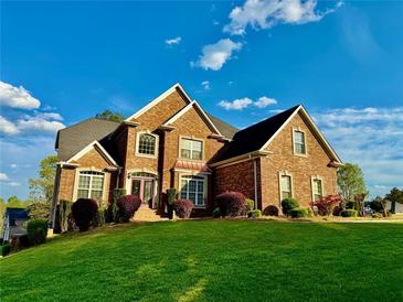 Beautiful two-story brick home featuring a manicured lawn and landscaping with colorful bushes at 3240 Letha Woods Sw Dr, Conyers, GA 30094