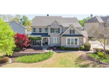 Beautiful two-story home featuring brick facade, covered front porch, and manicured landscaping at 147 Johnston Farm Ln, Woodstock, GA 30188