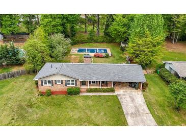 Expansive yard with brick home, driveway, and in-ground pool surrounded by mature trees at 690 Manor Ridge Sw Dr, Mableton, GA 30126