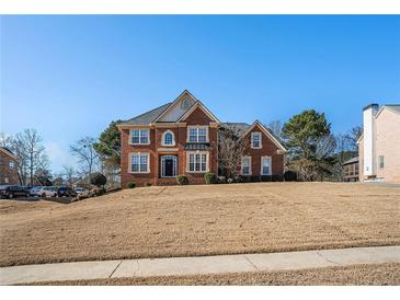 Two-story brick home featuring a manicured lawn, symmetrical windows, and a black front door at 104 Lumby Ln, Stockbridge, GA 30281
