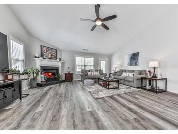 Spacious living room boasts a fireplace, ceiling fan and wood flooring at 305 Nobleman Way, Canton, GA 30114