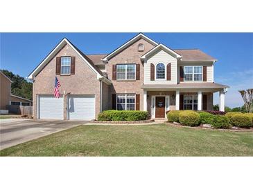 Charming two-story brick home featuring a well-manicured lawn, covered porch, and a two-car garage at 209 Crestmont Way, Canton, GA 30114