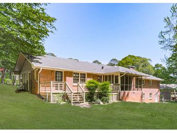 Expansive backyard featuring a brick house, wooden deck with stairs, and well-maintained lawn surrounded by mature trees at 4307 Smithsonia Ct, Tucker, GA 30084