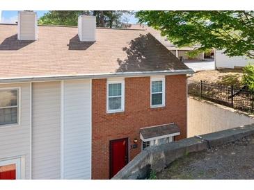 Charming townhouse featuring brick facade, red door, and well-maintained landscaping, offering curb appeal at 200 High Creek Dr, Roswell, GA 30076
